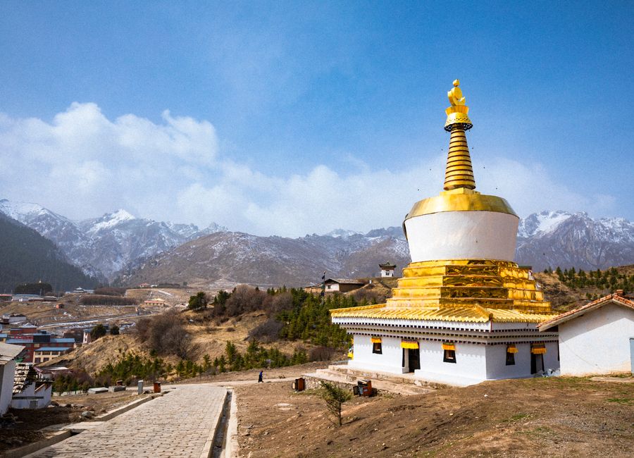 A stunning golden stupa amid a picturesque mountain setting with clear skies.