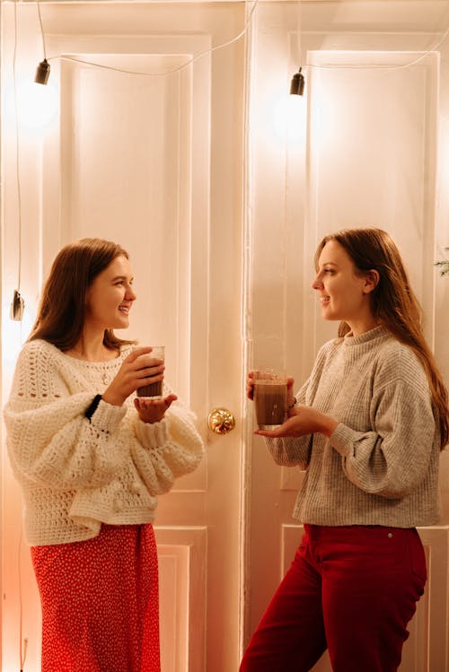 Two Women Wearing a Sweater While Holding a Drink