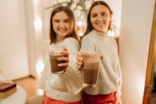 Blur Photo Of Two Young Girls Holding Glasses Of Chocolate Drinks