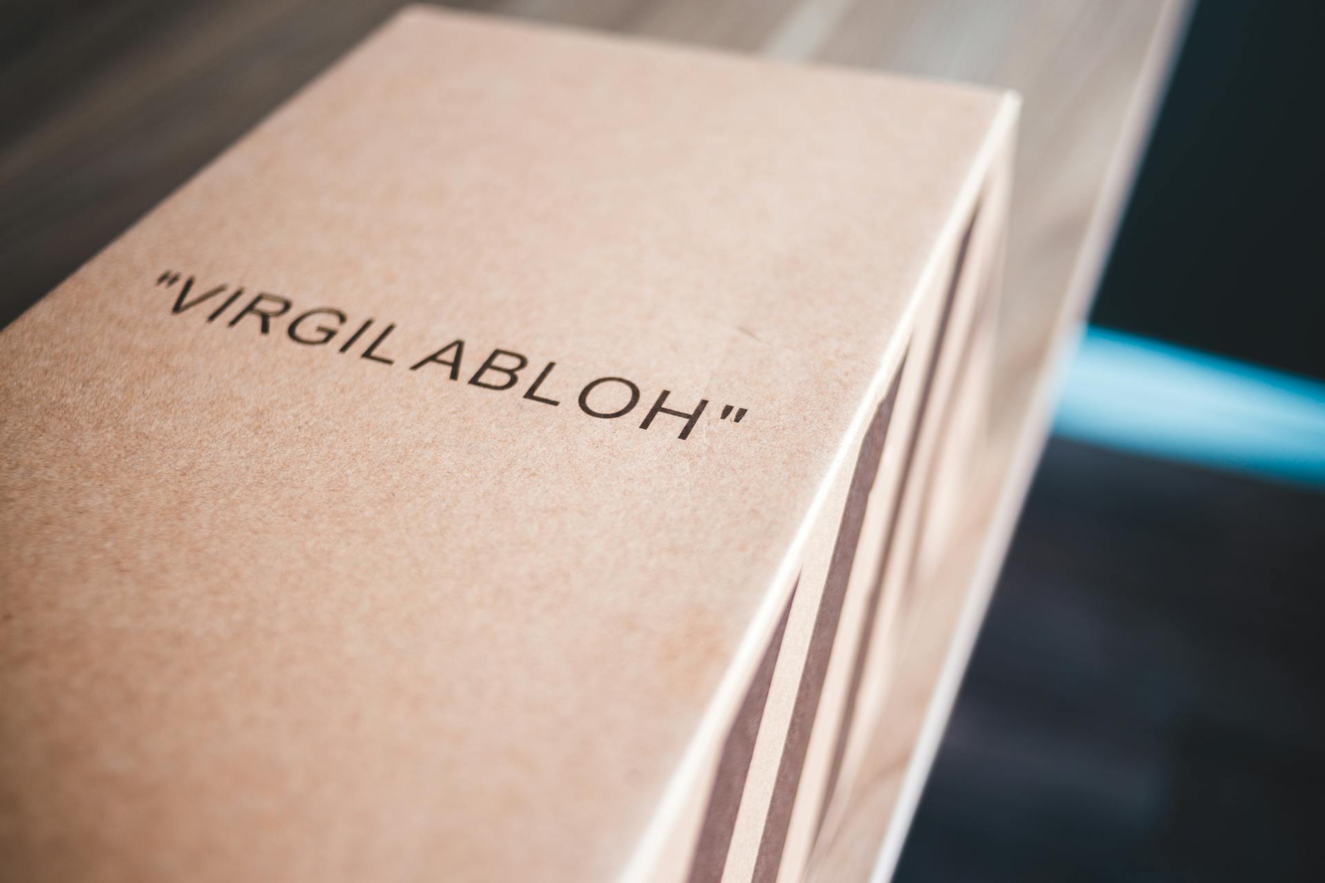 Close-up image of a cardboard box labeled 'VIRGIL ABLOH' on a table indoors.