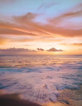Experience a stunning Hawaiian sunset with vibrant colors and gentle waves at the beach.