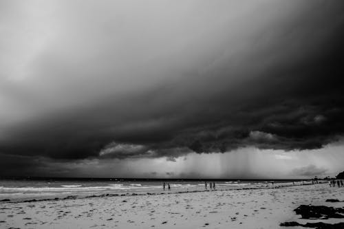 Grayscale Photo of the Thick Clouds Above the Beach