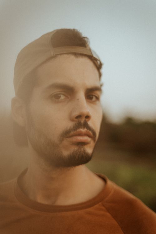 Free Portrait of a thoughtful man with a cap, captured outdoors with a soft, earthy tone. Stock Photo