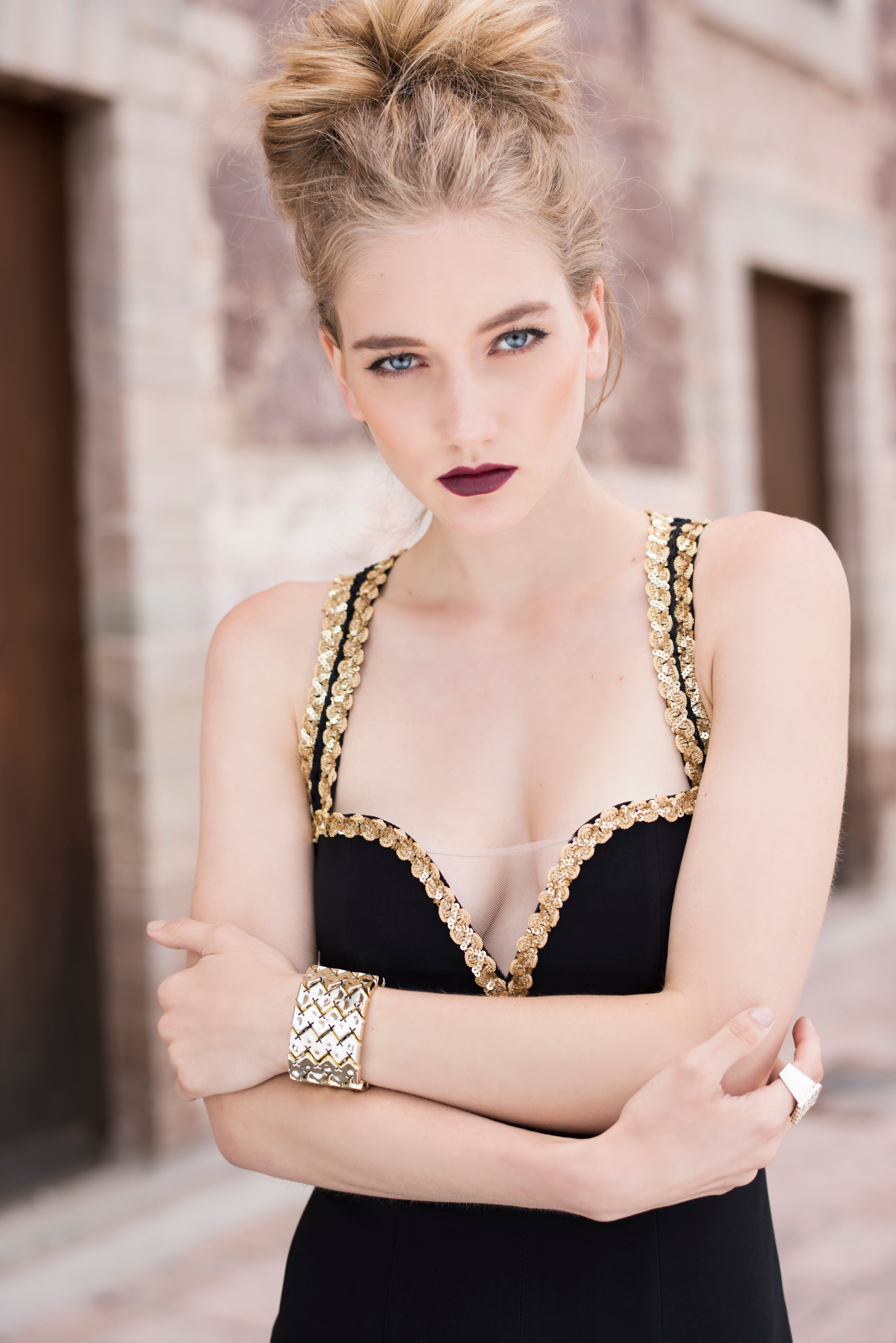 Stylish woman in an elegant black and gold dress posing confidently outdoors.
