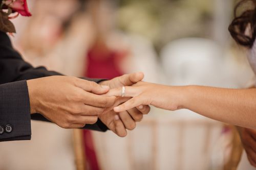 Free Side view of crop anonymous groom putting ring on finger of beloved during wedding ceremony Stock Photo