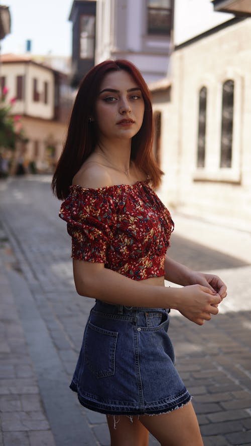 Dreamy teen in trendy clothes on city street