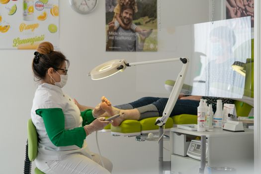 A podiatrist provides foot care to a patient in a clinical setting.