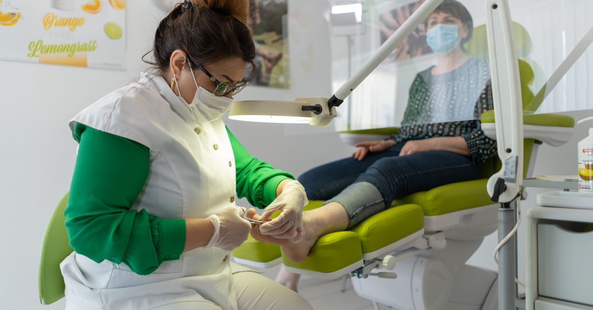 A beautician provides a pedicure in a modern spa setting, focusing on foot care and relaxation.