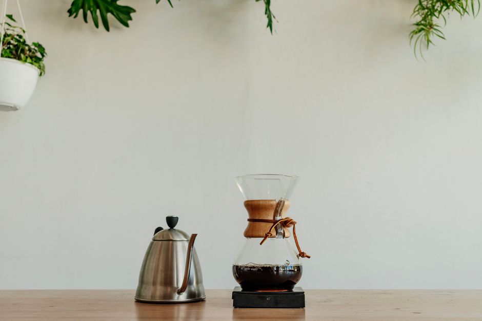 How Electric Kettles with Temperature Control Elevate Pour Over Brewing A minimalist coffee setup featuring a Chemex and kettle in a plant-decorated space.