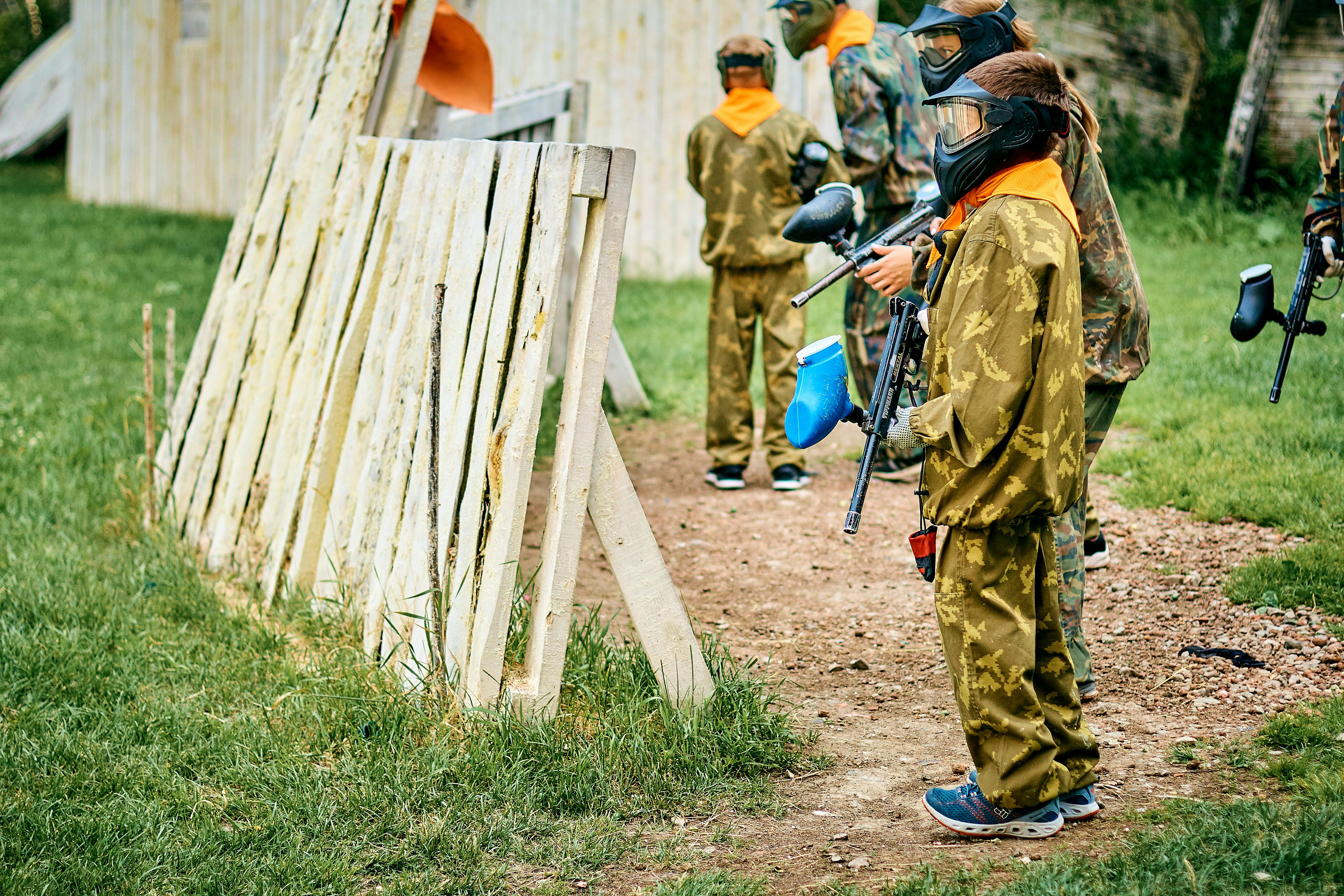Children engaged in a paintball game outdoors, wearing camouflage gear and protective masks for safety. Prescription Goggle Inserts - Children engaged in a paintball game outdoors, wearing camouflage gear and protective masks for safety.