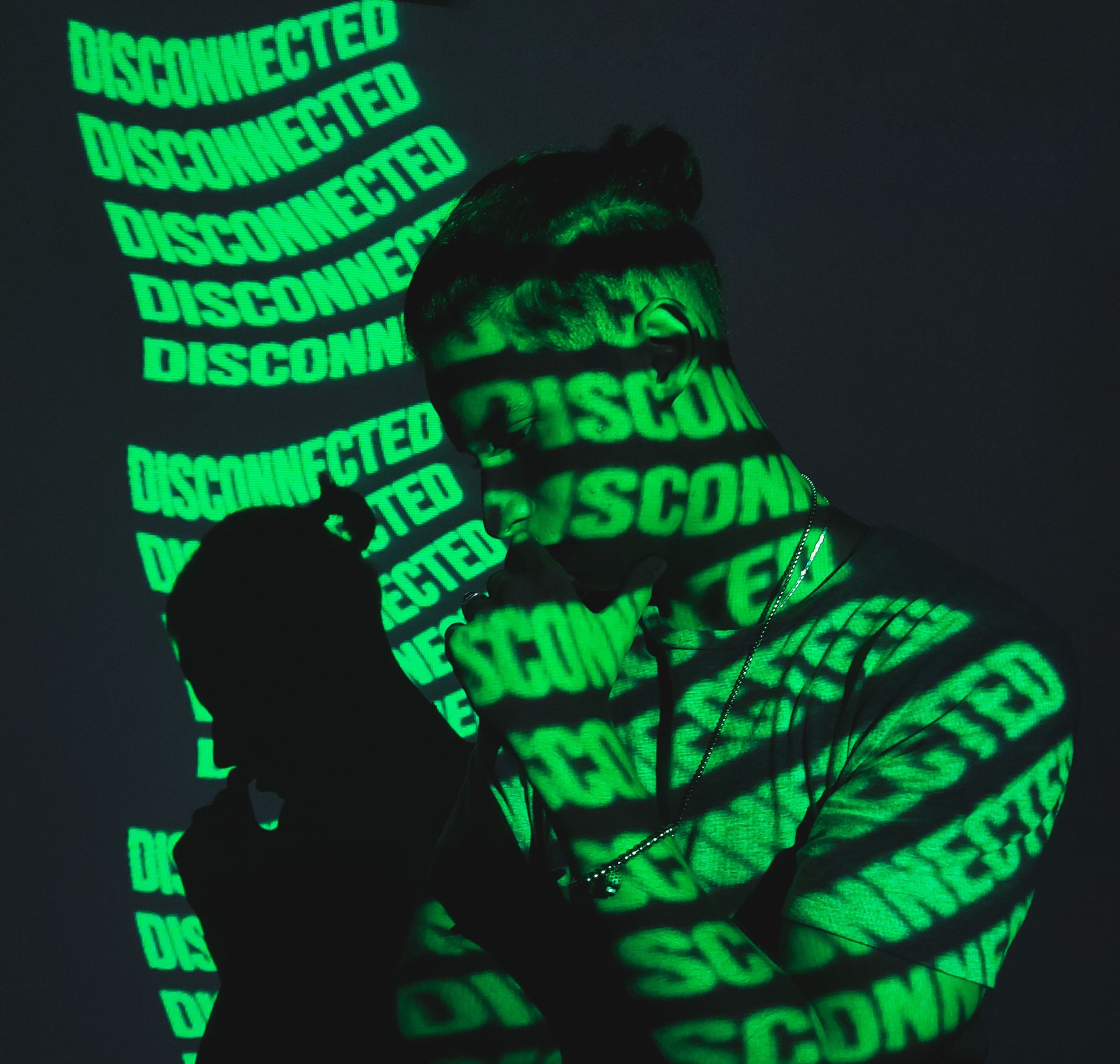 A man stands in shadow with 'Disconnected' text projected on him, creating a tech-themed silhouette.