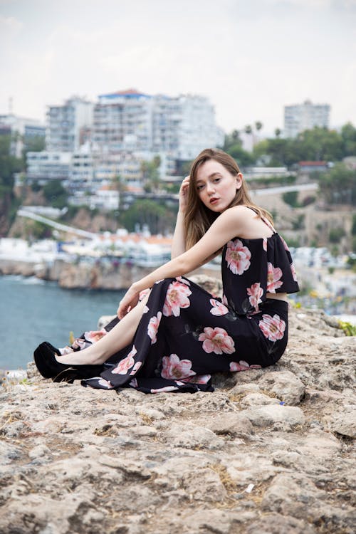 Stylish adolescent resting on rough terrain near city river