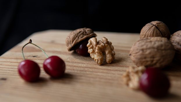 Crunchy walnuts and sweet cherries on cutting board