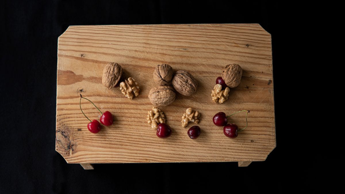 Walnuts and fresh cherries on a wooden board — two foods that naturally contain melatonin.