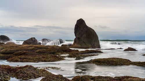 Free Tranquil ocean waves crash over rocky shores under an overcast sky. Stock Photo