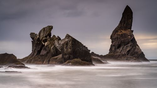 Free Scenic view of unique rock formations rising from the ocean, captured at dusk with a misty atmosphere. Stock Photo