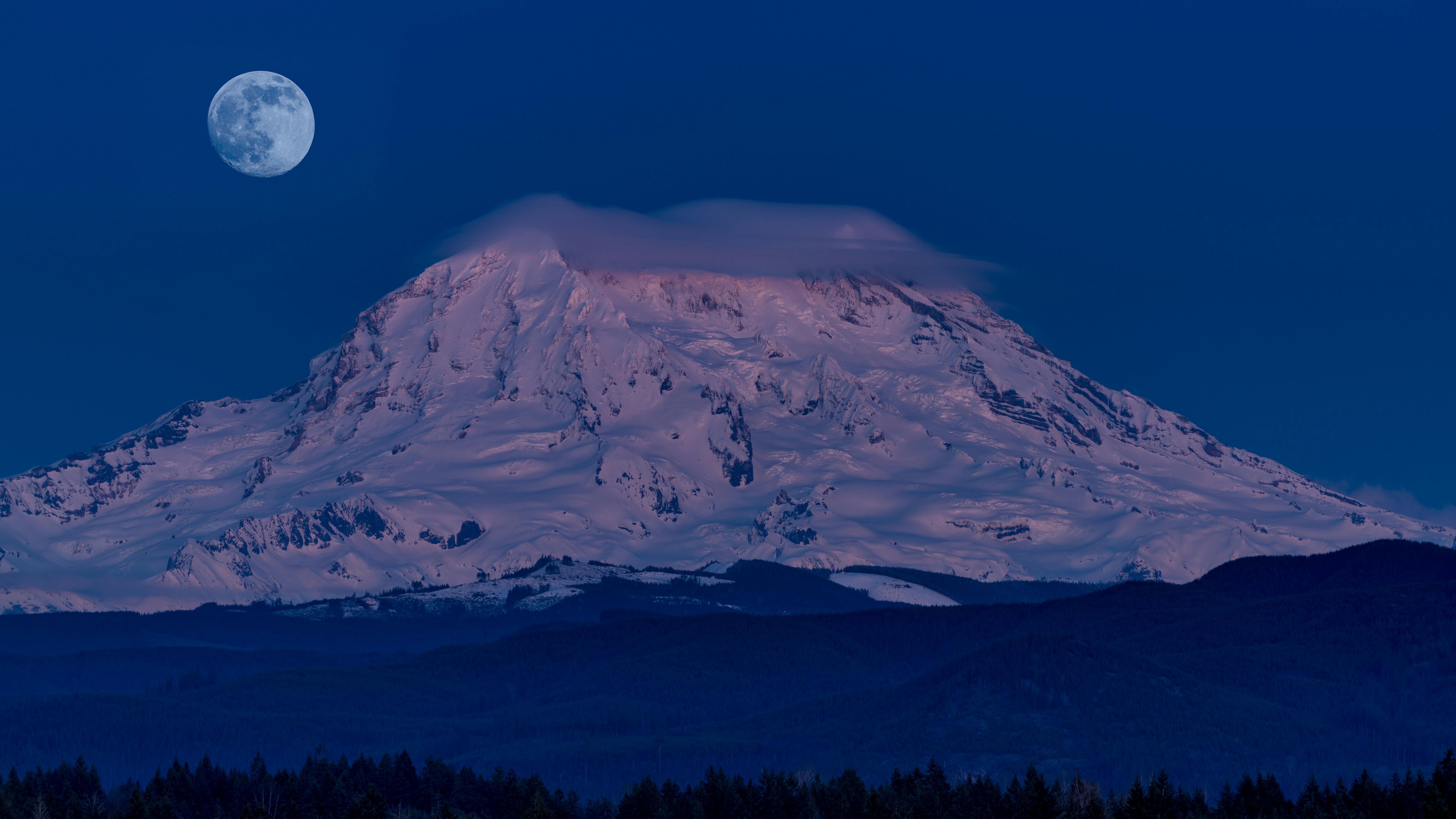 Breathtaking night view of Mount Rainier covered in snow under a full moon, WA, USA.