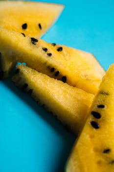特写镜头下，鲜艳的黄色西瓜片上，明亮的蓝色表面点缀着黑色种子