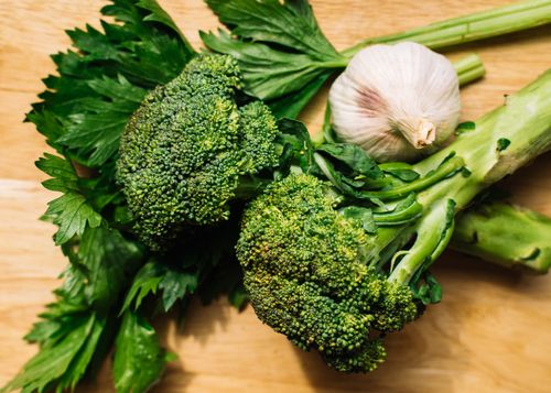 Free Close-up of fresh broccoli and garlic with celery on a wooden board, highlighting organic and healthy eating. Stock Photo