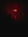 Unrecognizable people standing in dark room near red exit sign