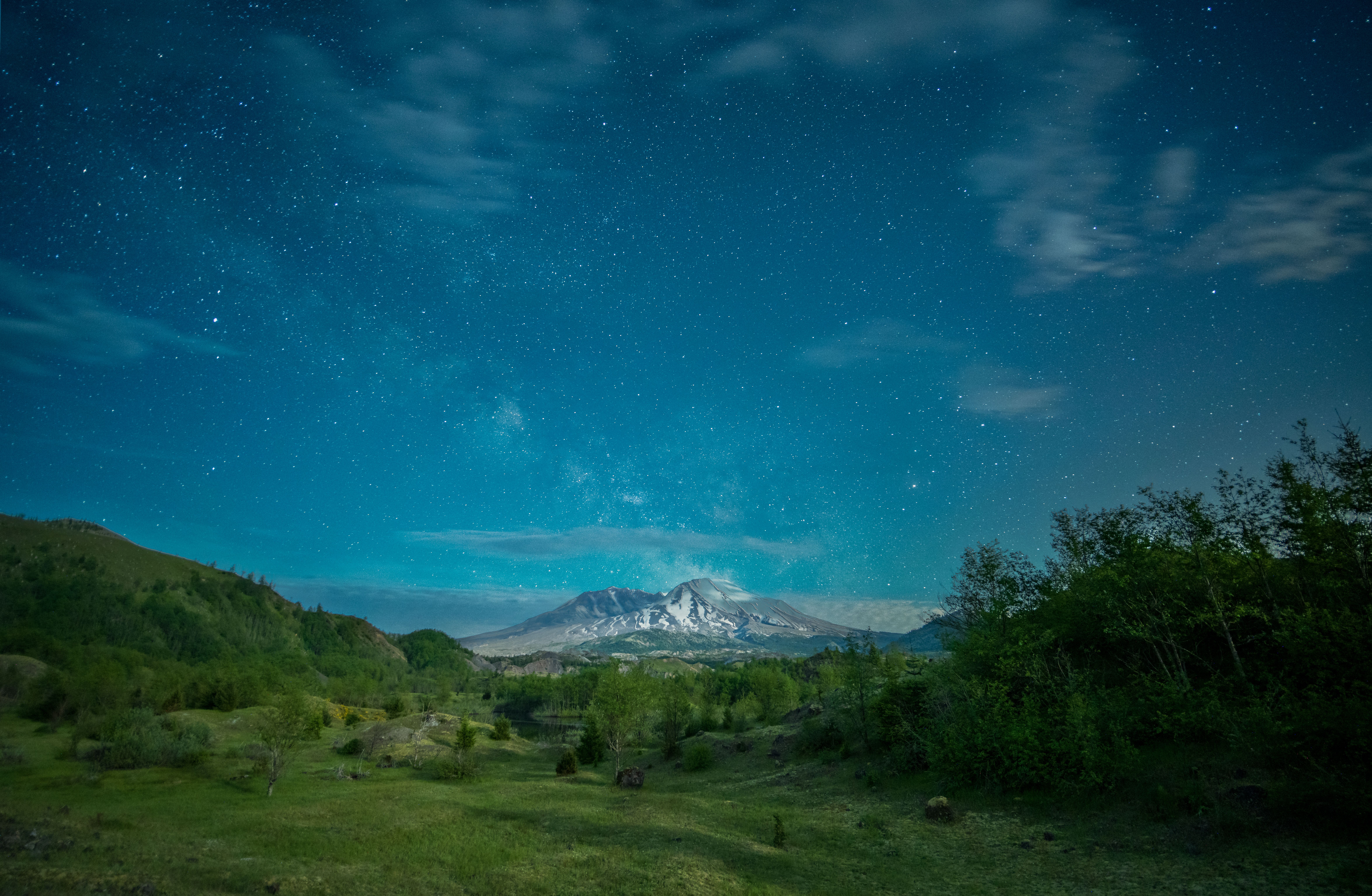 宁静的夜色中，郁郁葱葱的青山与远处白雪皑皑的山脉上，星空悄然呈现
