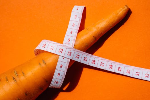 Close-up shot of a carrot wrapped with a measuring tape on a vibrant orange background, symbolizing healthy eating.