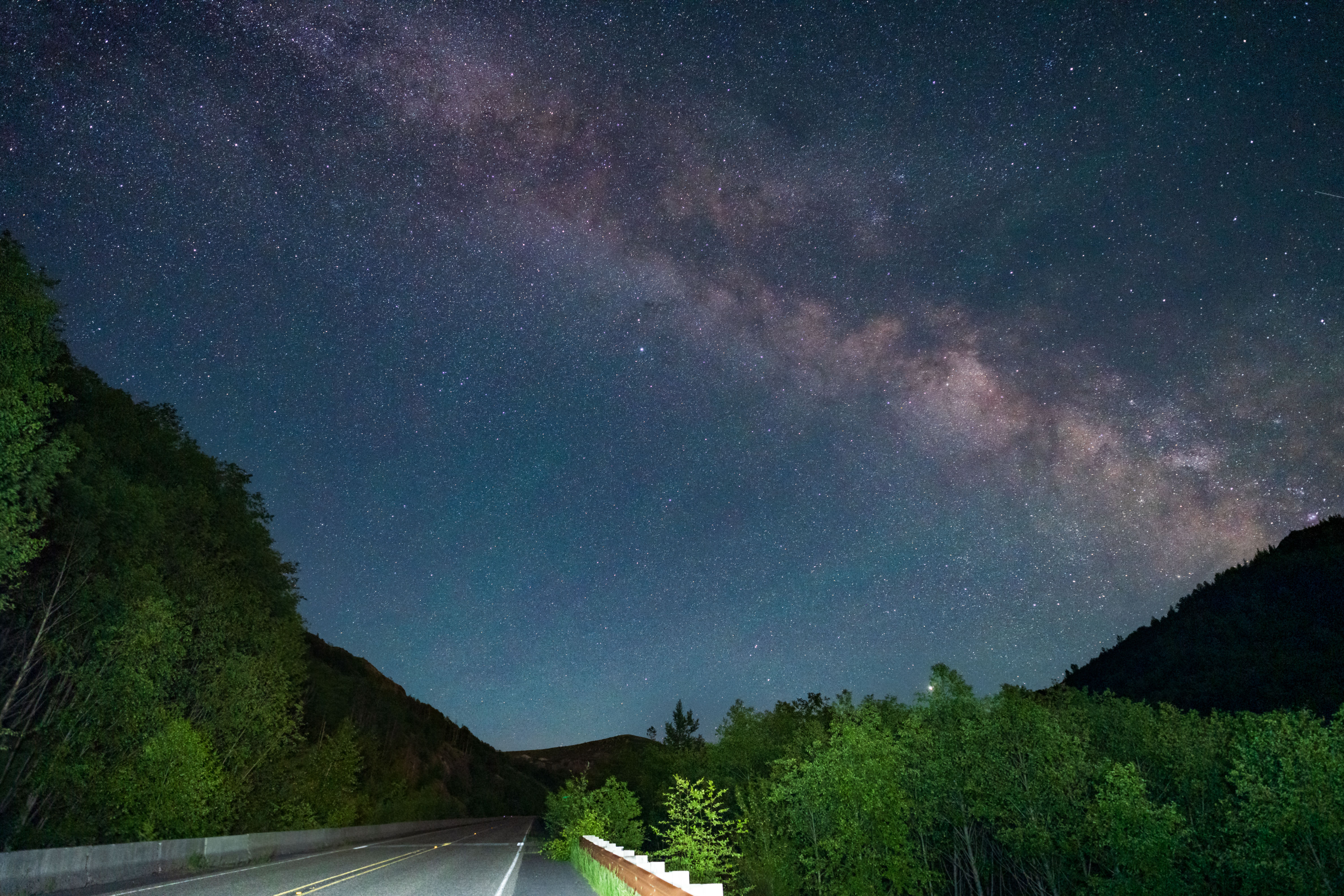 夜晚，从宁静的森林道路上方俯瞰，银河的壮丽景色尽收眼底