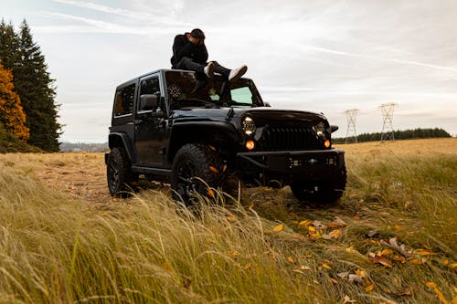 Person Sitting on the Roof of Black Jeep Wrangler
