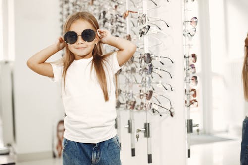 A Young Girl Wearing Sunglasses and a White Shirt