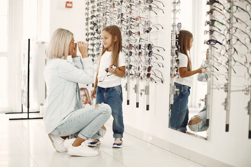 A Woman and a Young Girl Looking at Each Other while Holding a Sunglasses