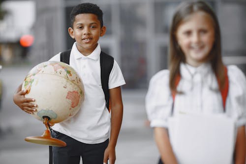 Free A Boy in White Button Up Shirt Carrying a World Globe  Stock Photo