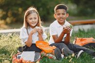 Happy Kids Sitting on Grass Eating Lunch