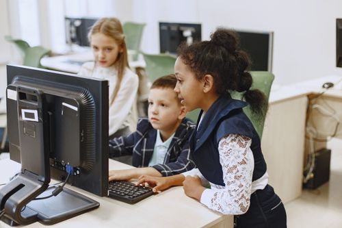 Diverse group of children working together on computers