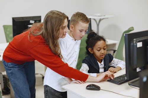 Free Teacher Helping Students with Computer Problems Stock Photo