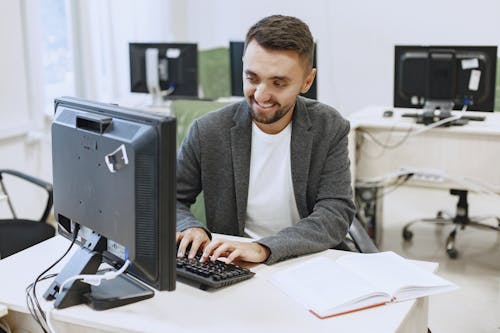 A Man Smiling while Typing on Keyboard