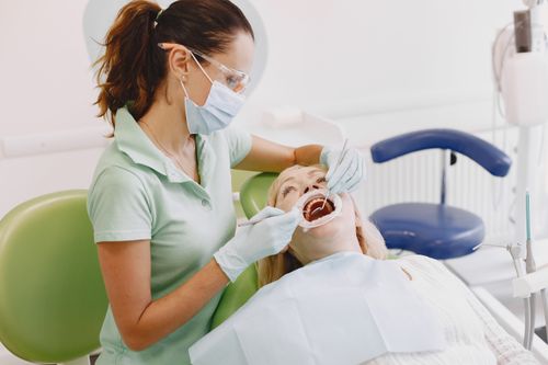 Free Female dentist examining senior woman's teeth in a dental clinic setting. Stock Photo