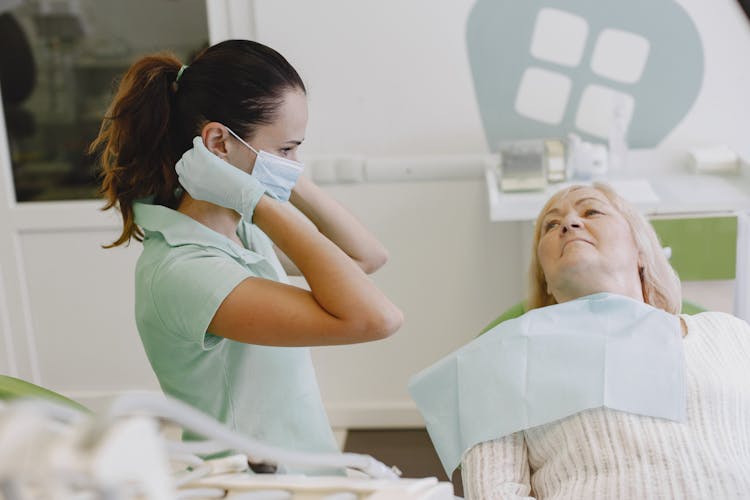 An Elderly Woman Looking At The Dentist Wearing Face Mask