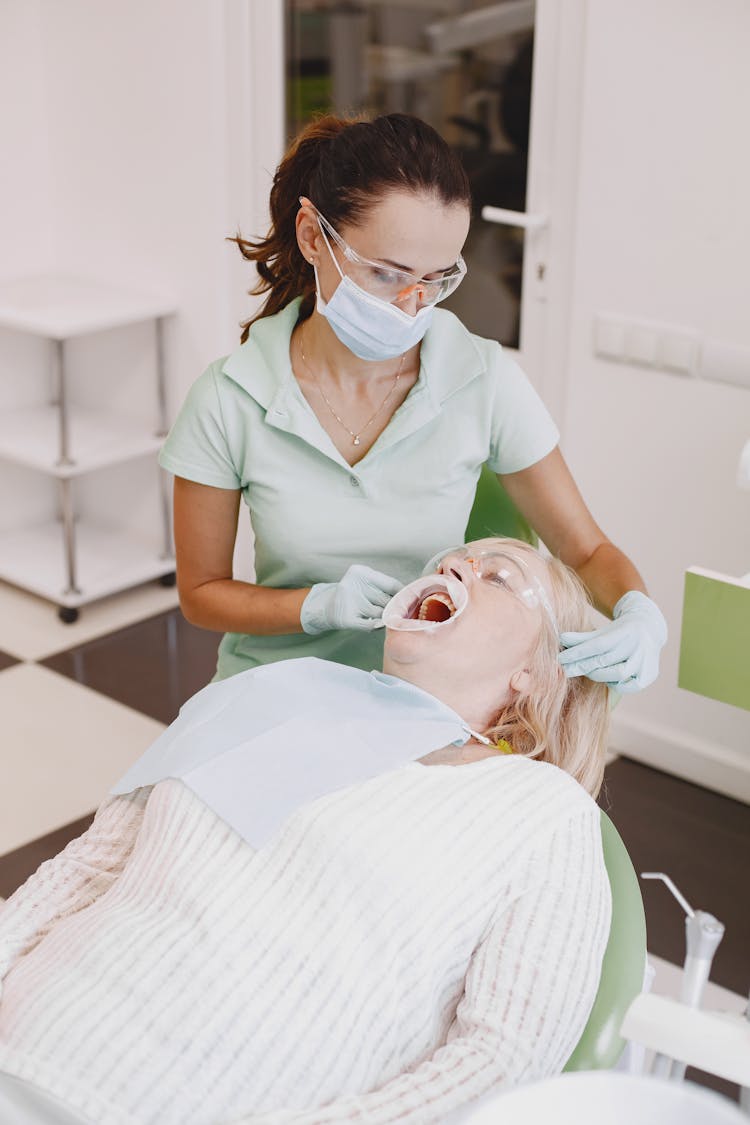 A Dentist Looking At Her Patient With Dental Cheek Retractor