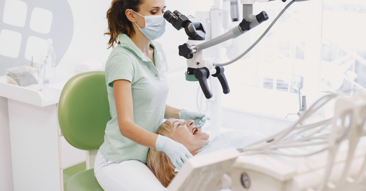 Dentist performing an examination using a microscope in a bright dental clinic.
