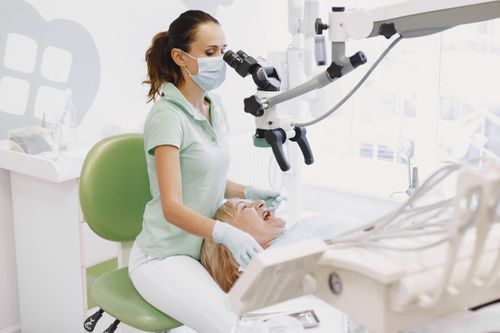Free Dentist performing an examination using a microscope in a bright dental clinic. Stock Photo