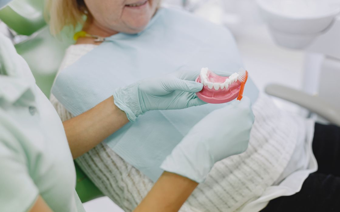 Dental professional showing a senior patient how to clean a denture