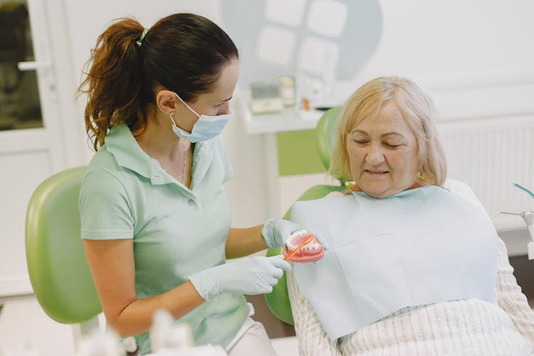 A Dentist Showing An Elderly Woman Her Denture
