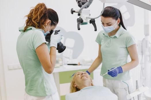 Dentists with hygienic gear assisting a patient in a professional dental clinic, ensuring comfort and care.