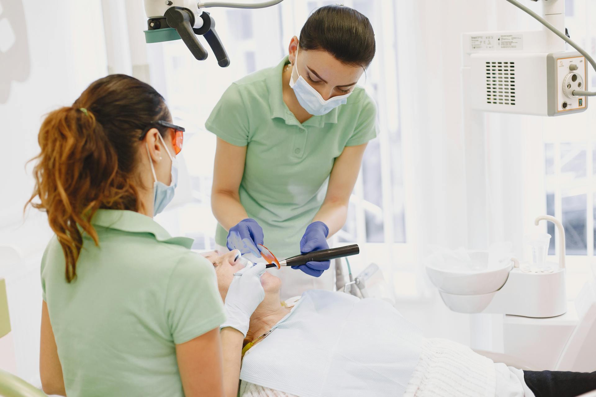 Dentists performing a dental procedure on a patient in a bright, modern clinic.