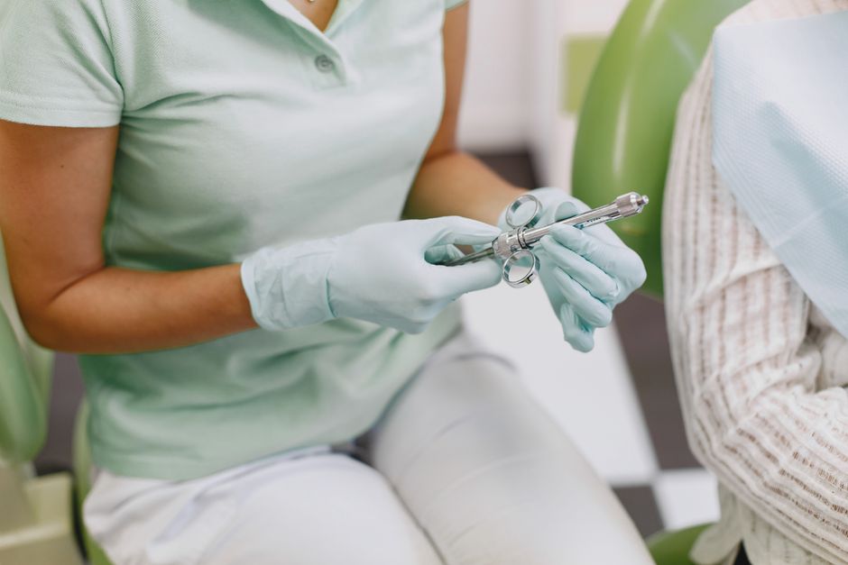 Dentist holding a sterile tool, preparing for a dental procedure in a clinic.
