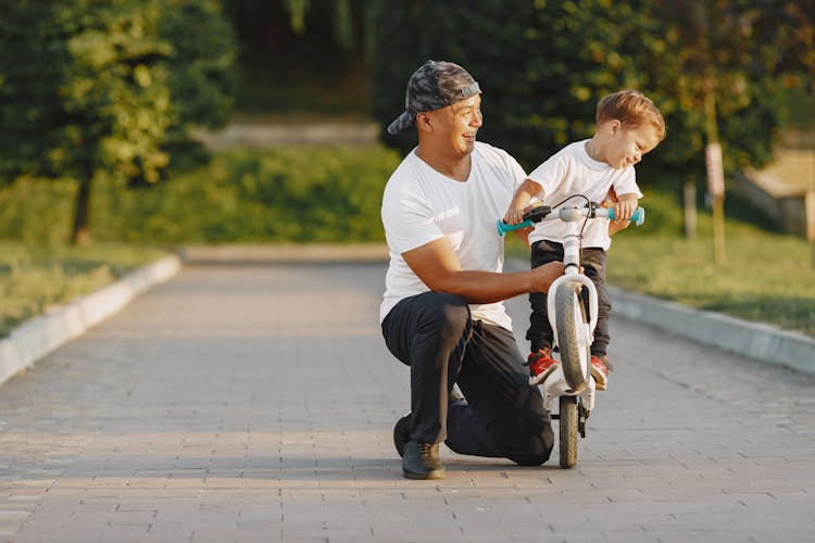 A Man Guiding His Son Riding A Bike