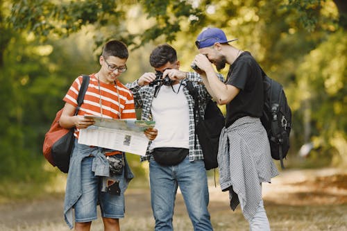 Free Three Young Hikers Looking at Map Stock Photo