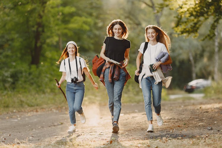 A Group Of Women Running On A Dirt Road