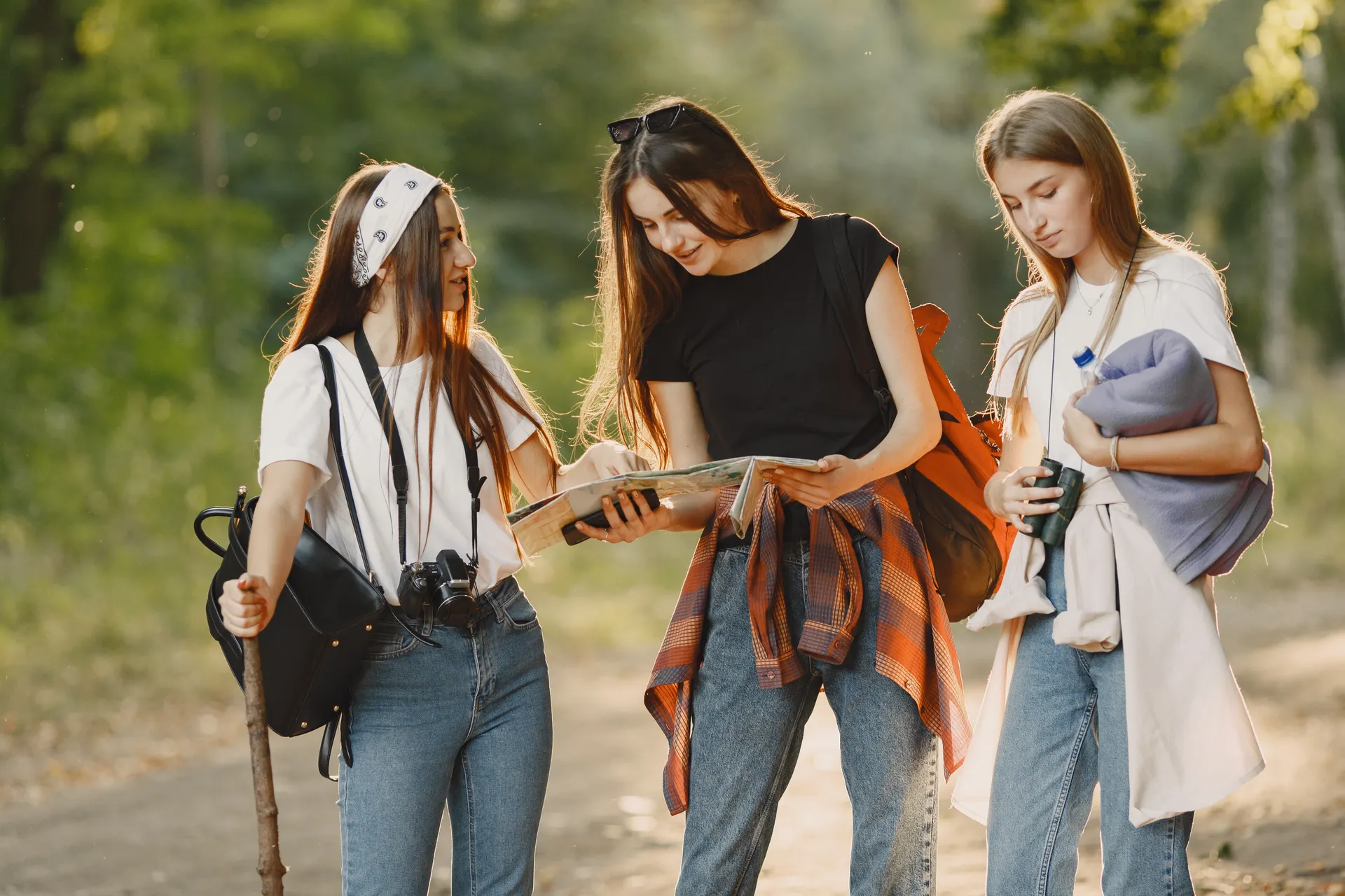 Three women hiking a forest trail together and reading a map Three women hiking a forest trail together and reading a map