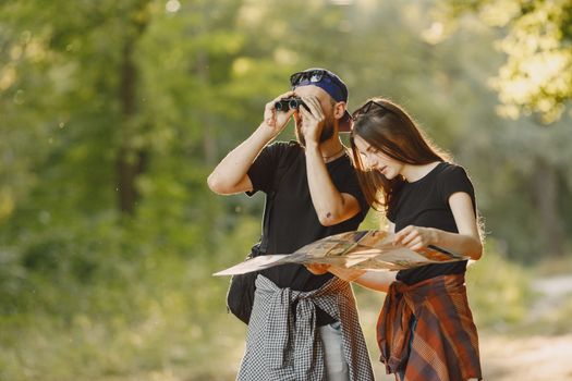 A couple outdoors using binoculars and a map for an adventure journey.